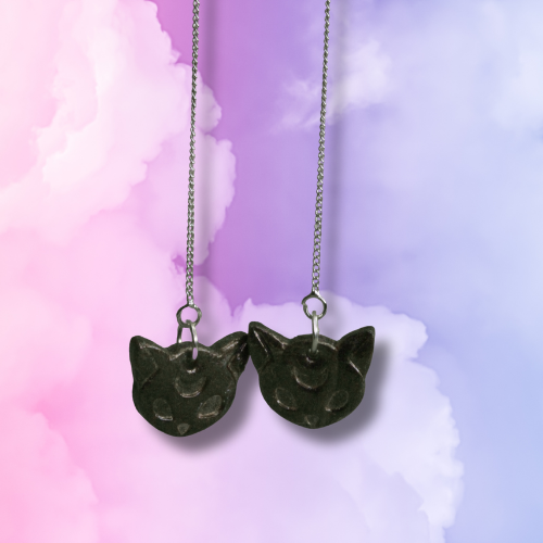 Cat-shaped thread earrings on a pastel gradient background